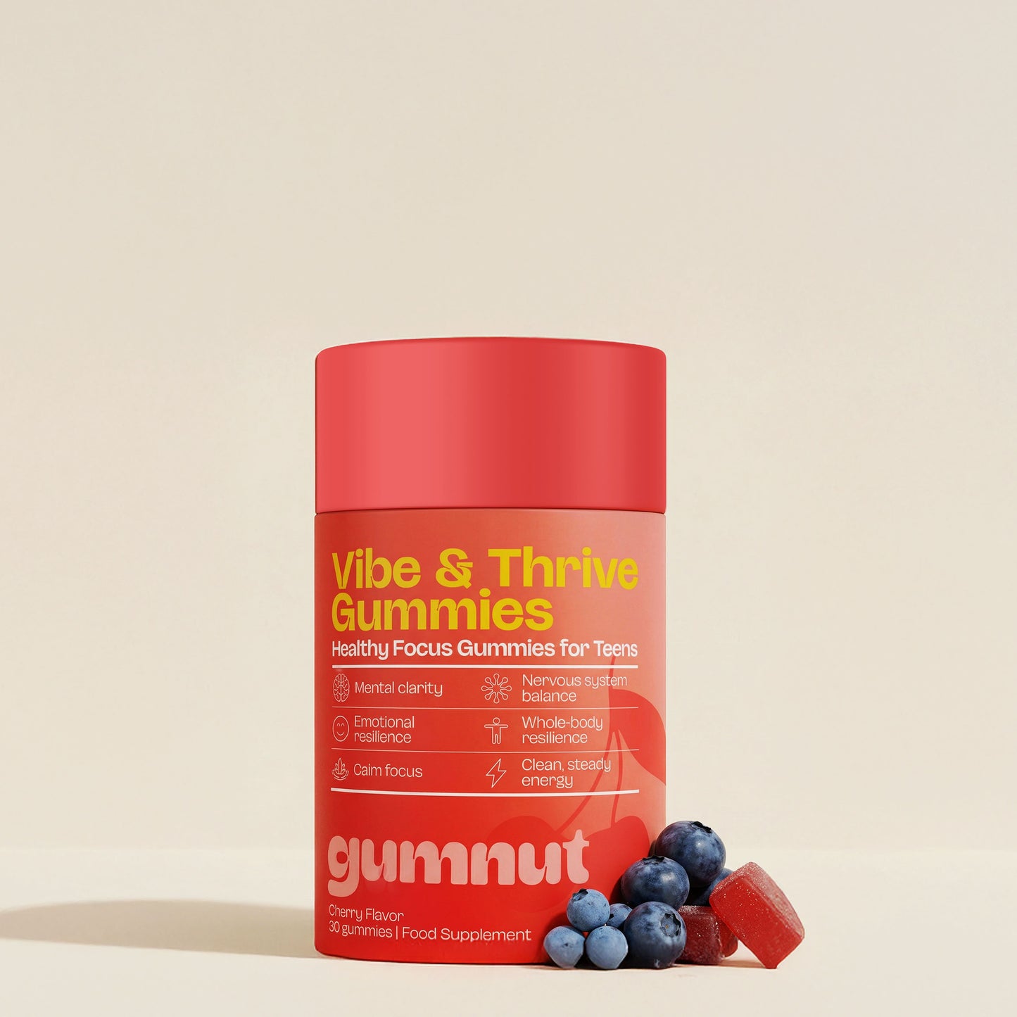 Red container of Vibe & Thrive Gummies with blueberries and gummy bears on a beige background